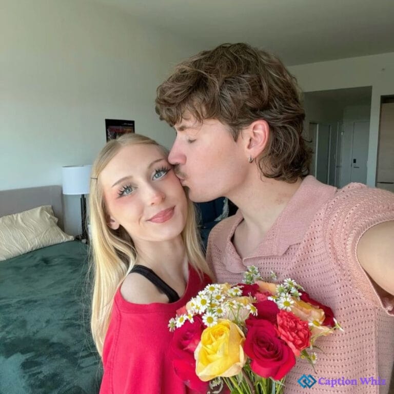 Couple smiling, woman holding flowers, man kissing her on cheek.