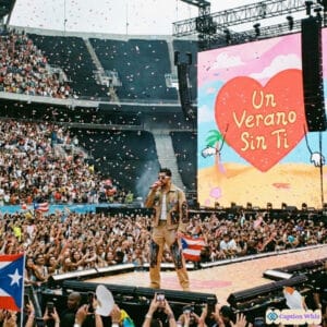 A lively concert scene with a performer on stage, colorful confetti falling, and a large screen displaying bright graphics.